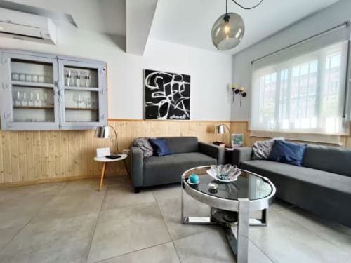 Moderno salón de apartamento en Fuengirola con sofás grises, revestimiento de madera y arte contemporáneo