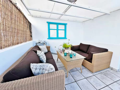 Acogedor salón de apartamento en Fuengirola con muebles de mimbre, ventana turquesa y pared de madera