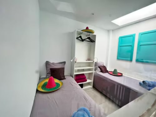 Acogedor dormitorio en apartamento de Fuengirola con camas gemelas, decoración colorida, puertas turquesas y claraboya moderna
