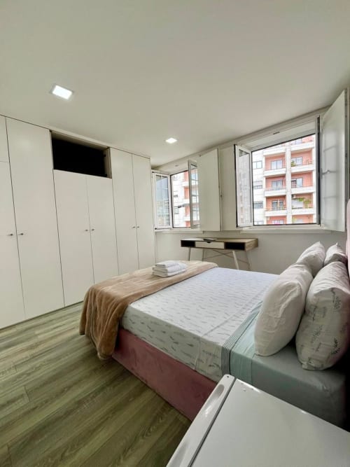 Modern bedroom at Casa Augusta hostel in Braga with double bed, white wardrobes, desk, and city views