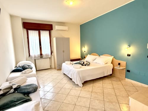 Spaziosa camera quadrupla all'Hotel Il Mulino con parete azzurra, letti gemelli, aria condizionata e pavimento piastrellato