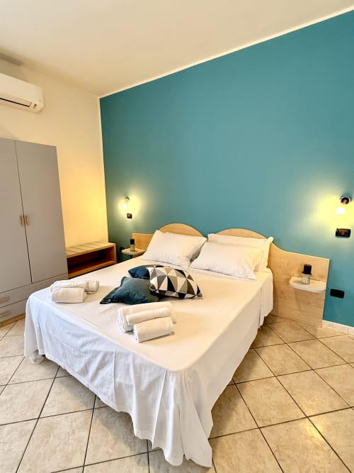 Camera quadrupla standard all'Hotel Il Mulino di Casalgrande con letto matrimoniale, parete d'accento turchese e bagno privato