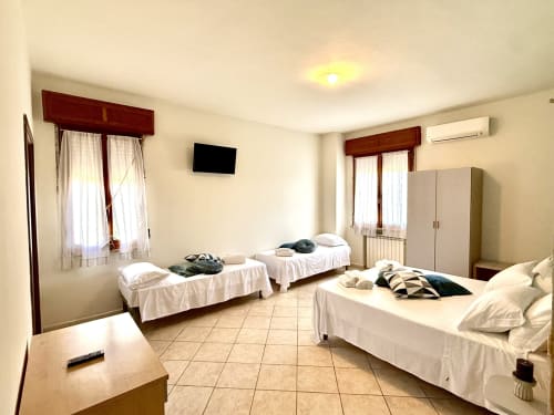 Camera quadrupla standard dell'Hotel Il Mulino con più letti, bagno privato, TV e finestre con persiane in legno
