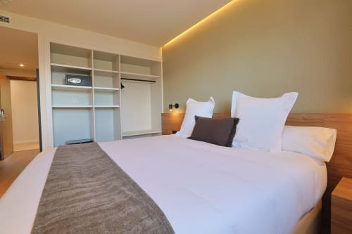 Modern accessible hotel bedroom at Hotel Fonsispa with white bedding, wooden headboard, and built-in wardrobe in Renanué