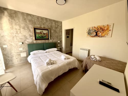 Moderno triple room presso BBSASSUOLO.IT a Sassuolo con testata verde, biancheria bianca e arredamento contemporaneo