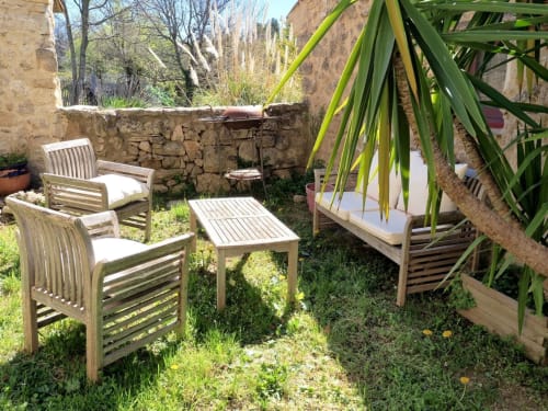 Cour rustique en pierre du gîte Bastide Saint Michel avec chaises en bois, verdure et murs en terre cuite