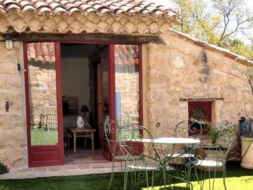 Cottage Le Tournesol à la Bastide Saint Michel avec toit en terre cuite, murs en pierre, portes rouges et salon de jardin