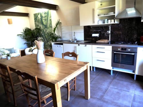 Cuisine moderne et coin repas du gîte Le Mosaïque à la Bastide Saint Michel, avec table en bois, mobilier blanc et vue sur le jardin