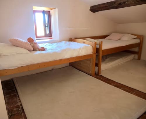 Trois lits en bois dans la chambre lumineuse de la Bastide Saint Michel, Baudinard sur Verdon, avec fenêtre et poutre apparente