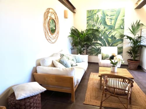 Chambre de la Bastide Saint Michel avec canapé blanc, plantes tropicales, fauteuil en rotin et œuvres d'art de jardin à Bauduen sur Verdon