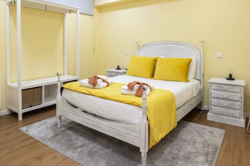 Bright yellow bedroom with white metal bed, yellow bedding, and white nightstands in RH Charming Apartments, Braga