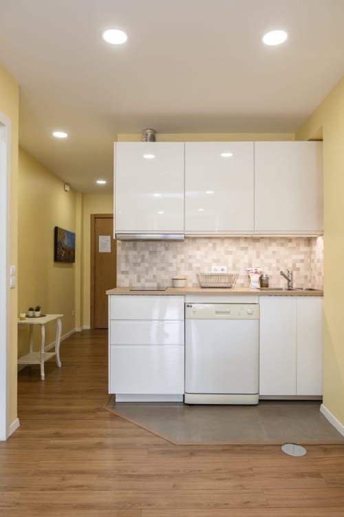 Modern kitchen in RH Charming Apartment Liberdade II, Braga with white cabinetry, dishwasher, and yellow walls