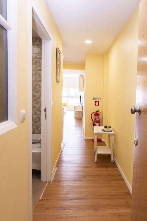 Bright yellow hallway in RH Charming Apartment Liberdade II, Braga, with wooden flooring, bathroom access, and fire safety