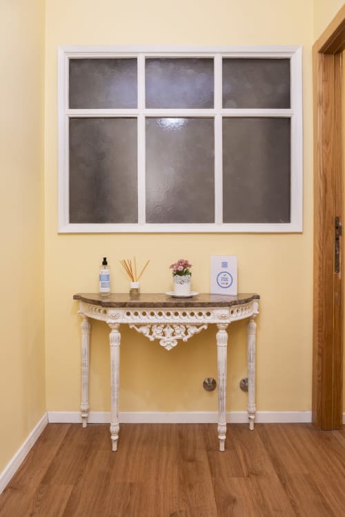 Elegant entryway with cream-colored walls, decorative console table with carved details, and six-panel window in RH Charming