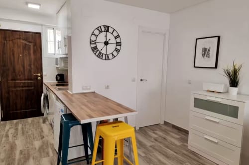 Apartamento estudio moderno en Fuengirola con isla de cocina, reloj de números romanos y mobiliario contemporáneo