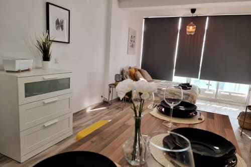 Apartamento estudio moderno en Fuengirola con zona de comedor, cocina, cama y vistas a la ciudad a través de grandes ventanales