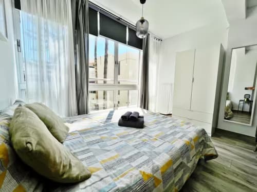 Moderno apartamento estudio en Fuengirola con vistas a la ciudad, cama con ropa de cama estampada y balcón amueblado