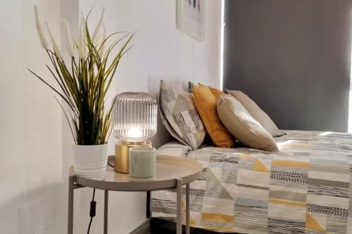 Interior moderno del apartamento de Fuengirola con planta decorativa, lámpara y ropa de cama estampada en sofá