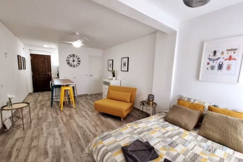 Moderno apartamento estudio en Fuengirola con sillón amarillo, cama y vistas a la ciudad