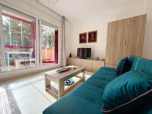 Luminoso estudio frente al mar en Fuengirola con sofá turquesa, muebles de madera y vistas a la ciudad