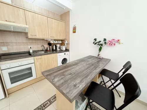 Cocina y comedor modernos en Fuengirola con muebles de madera, mesa de comedor y flores rosas