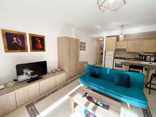 Luminoso apartamento estudio en Fuengirola con sofá turquesa, cocina americana y mobiliario moderno de Grupo Inmo House