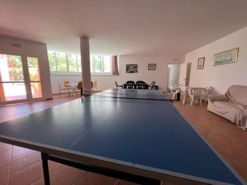 Amplia sala de recreación con mesa de ping pong, zonas de estar y acceso a terraza en apartamento de playa en Fuengirola