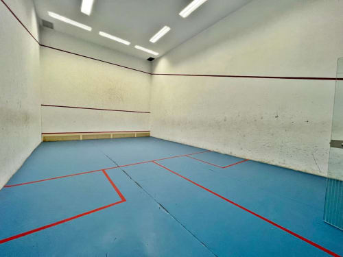 Cancha de squash vacía con piso azul y líneas rojas en apartamento Grupo Inmo House, Fuengirola