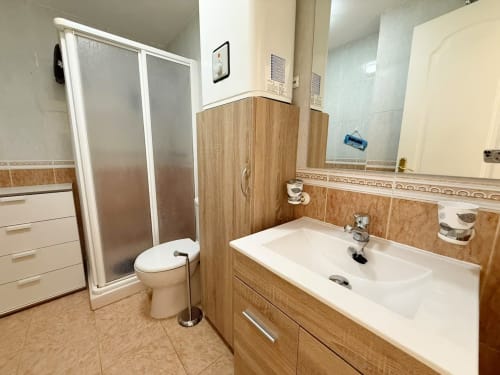 Baño moderno en apartamento de playa en Fuengirola con lavabo, inodoro, cabina de ducha y tocador de madera
