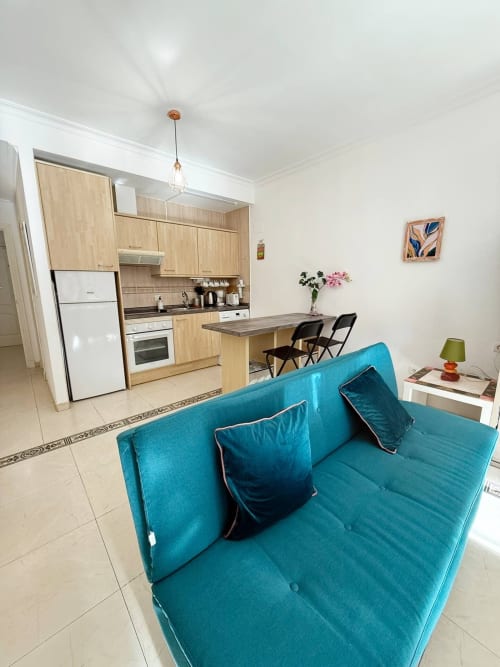 Luminoso apartamento estudio en Fuengirola con sofá turquesa, cocina de madera y vistas a la ciudad