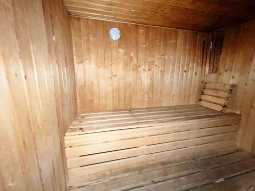 Interior vacío de sauna de madera con bancos y reloj de pared blanco en apartamento de Fuengirola