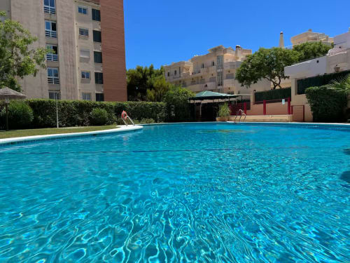 Piscina cristalina en el residencial Grupo Inmo House de Fuengirola con edificios modernos y cielo azul despejado
