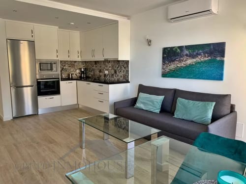 Moderno apartamento frente al mar en Fuengirola con cocina abierta, sofá oscuro, arte costero y vistas al mar