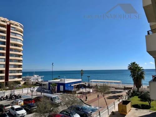 Vista del apartamento en primera línea de playa de Fuengirola con mar, palmeras y cielo azul en Grupo Inmo House