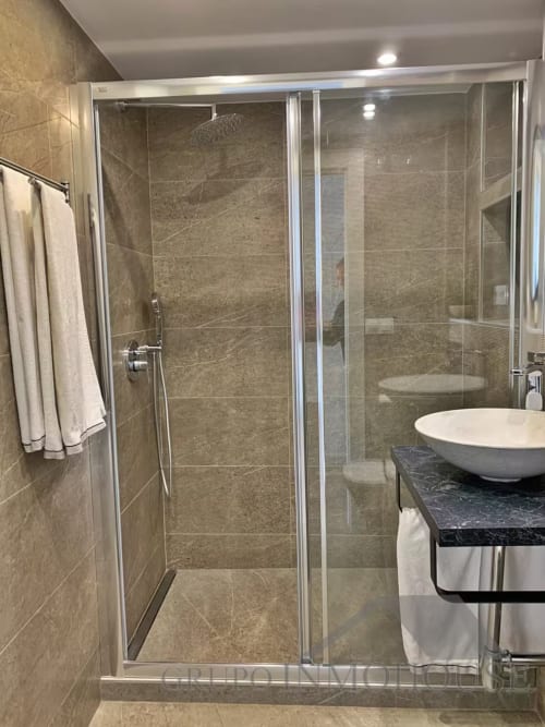 Baño moderno con ducha de cristal, tocador de mármol y azulejos beige en apartamento playa de Grupo Inmo House, Fuengirola
