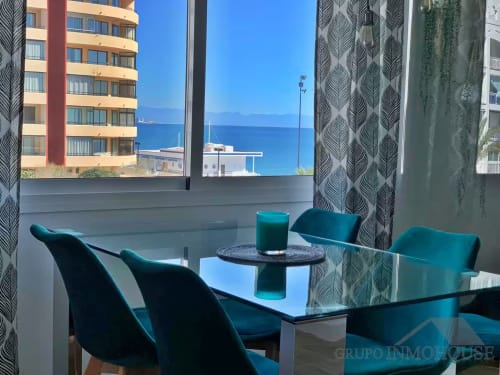 Lujoso apartamento de playa en Fuengirola con sillas turquesas, mesa de cristal, vistas al mar y costa mediterránea