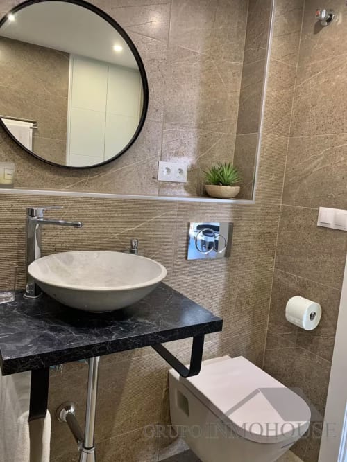 Baño moderno en apartamento de playa en Fuengirola con espejo redondo, lavamanos tipo vasija y azulejos con vistas al mar