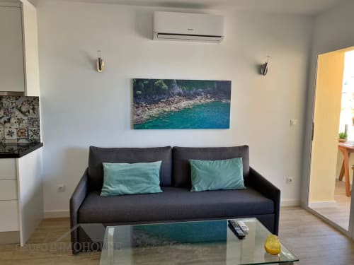 Apartamento moderno frente al mar en Fuengirola con sofá oscuro, cojines turquesas y decoración costera