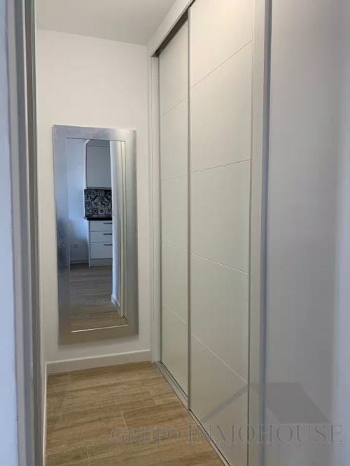 Moderno pasillo con armario de puertas espejadas en apartamento de playa en Fuengirola por Grupo Inmo House