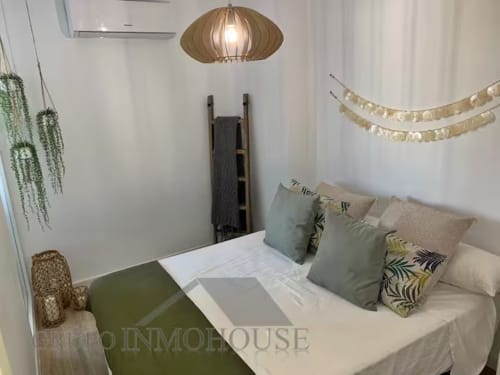 Dormitorio moderno en apartamento de playa de Fuengirola con cama queen, almohadas decorativas, lámpara colgante y vistas al mar