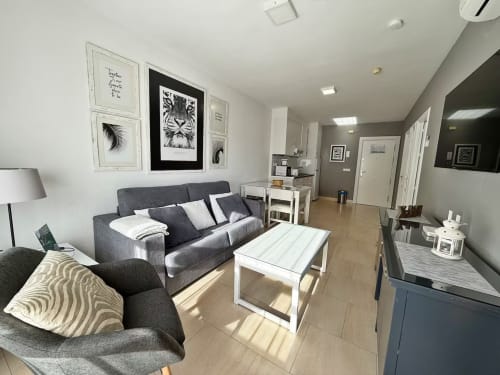 Moderno salón de apartamento frente al mar en Fuengirola con sofá gris, vistas al mar y muebles contemporáneos