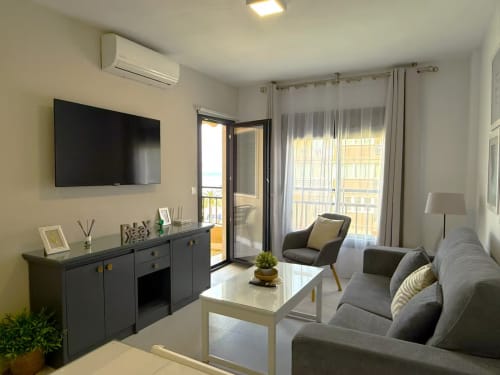 Moderno apartamento frente al mar en Fuengirola con vistas al océano, sofá gris, TV de pantalla plana y balcón