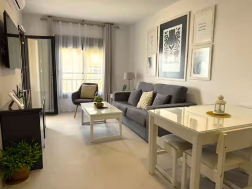 Apartamento moderno en Fuengirola con vistas al mar, sofá gris, zona de comedor y decoración contemporánea.