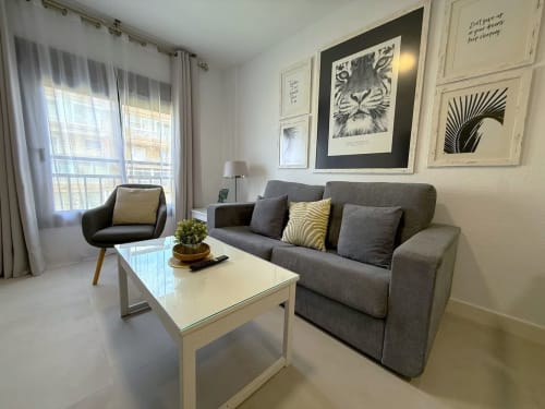 Sala de estar de apartamento frente al mar en Fuengirola con sofá gris, mesa de centro blanca y vistas al mar