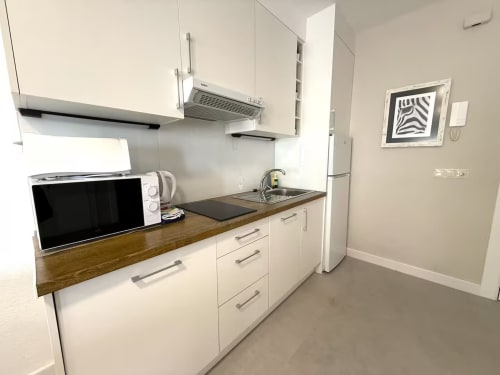 Cocina moderna blanca con encimera de madera, microondas, fregadero y electrodomésticos en apartamento frente al mar, Fuengirola