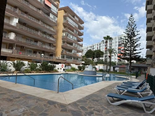 Apartamento en primera línea de playa de Fuengirola con piscina, vistas al mar, tumbonas y edificios de resort mediterráneo