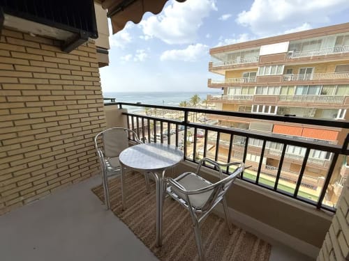 Balcón con vista al mar en apartamento frente a playa en Fuengirola con mesa y sillas de comedor con vistas al Mediterráneo