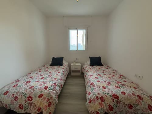 Dormitorio doble en apartamento frente al mar de Grupo Inmo House, Fuengirola con ropa de cama floral y vistas desde la ventana