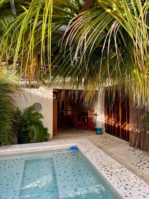Villa Tulum en Ala Residencias cuenta con piscina tropical, frondas de palma y villa con puerta de madera en Chetumal