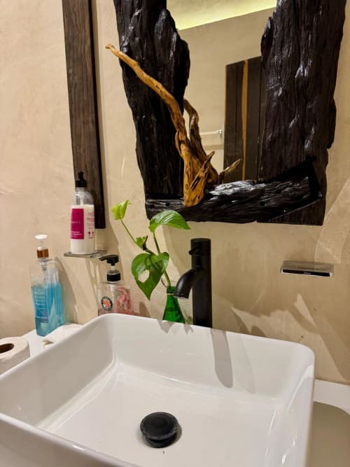 Baño moderno de Ala Residencias Villa Tulum con lavamanos blanco, espejo de madera negra, planta decorativa y amenidades en Chetumal